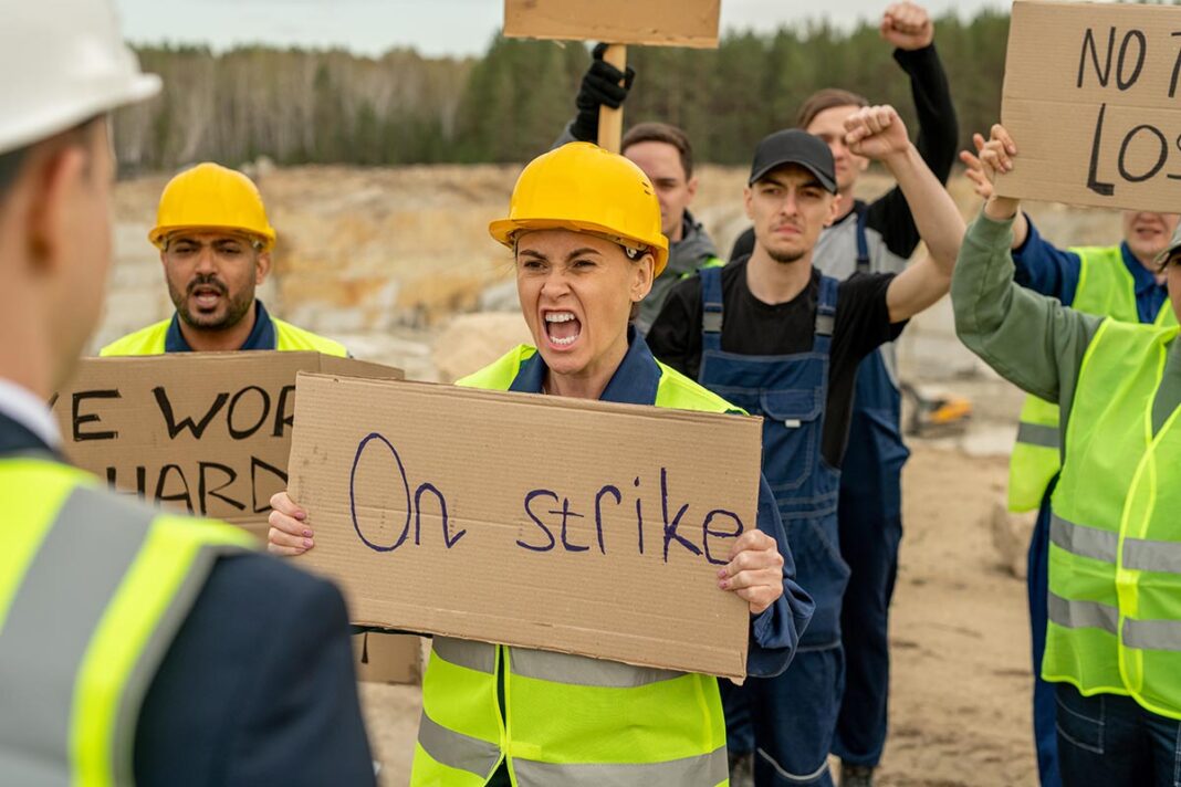 Furious female and other quarry workers carrying placards
